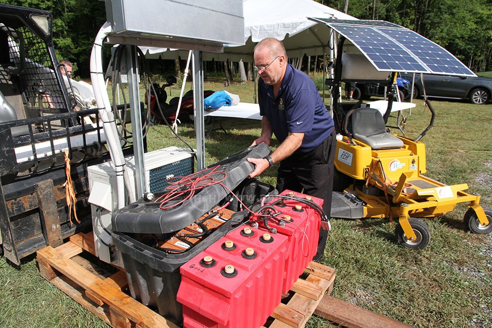 Hydrogen House Dedication 9/11/2015 Pennington NJ - Mike Strizki adjusting batteries in energy system in front of Hydrogen and solar powered lawn mower